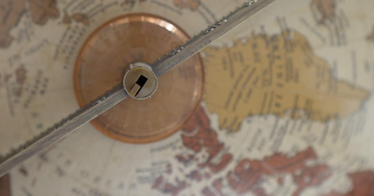 Close-up of a vintage desktop globe's axis and stand.